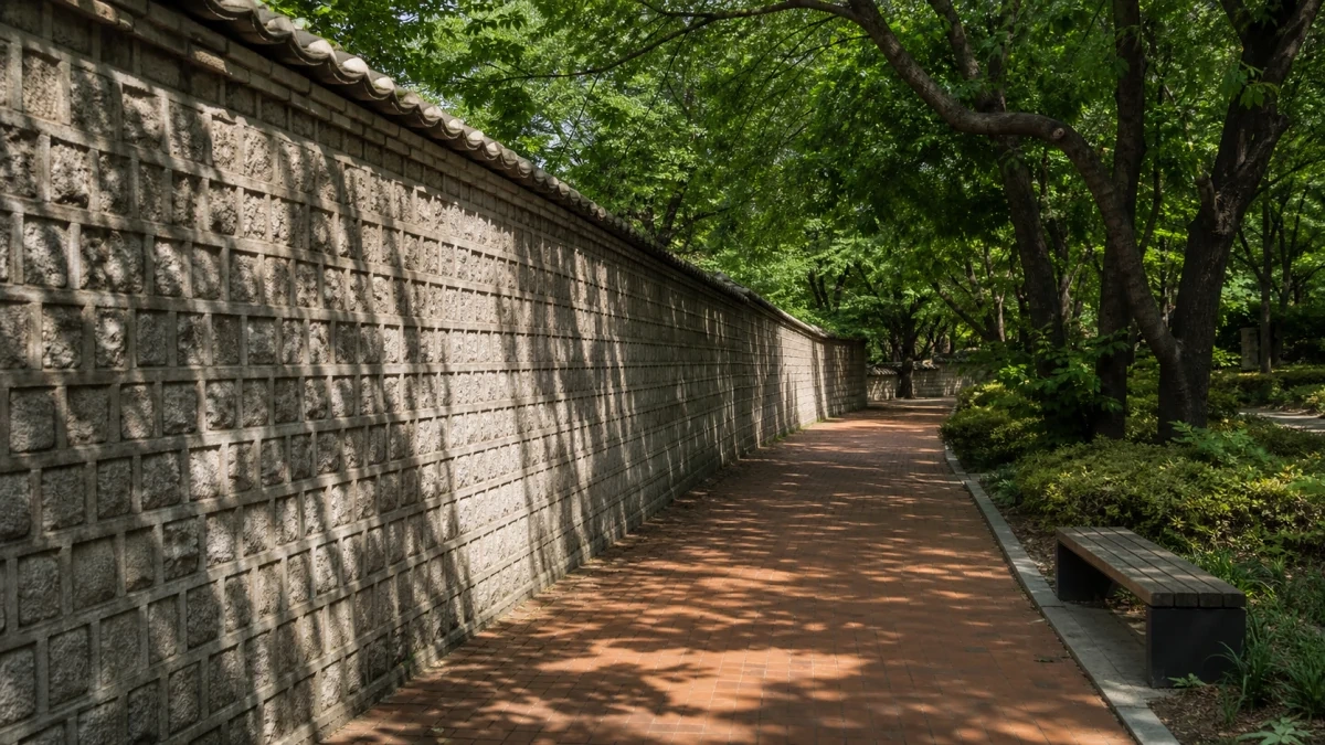 덕수궁 돌담길의 회색 돌담과 붉은 보도가 짙은 나무 그늘 아래 이어지는 장면