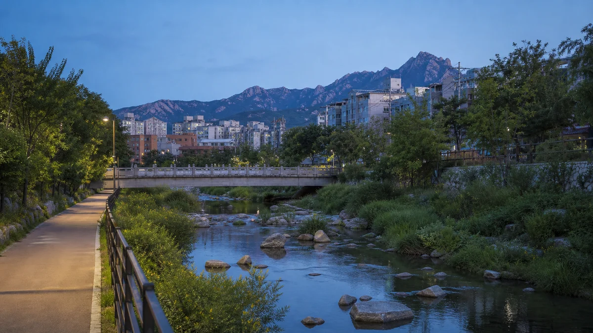 우이천 산책로의 물길·보행교·도시 가장자리에 저녁빛이 내려앉은 장면