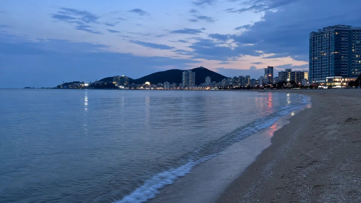 송도해수욕장에 도시 불빛과 잔잔한 수면이 겹치는 청색시간 풍경