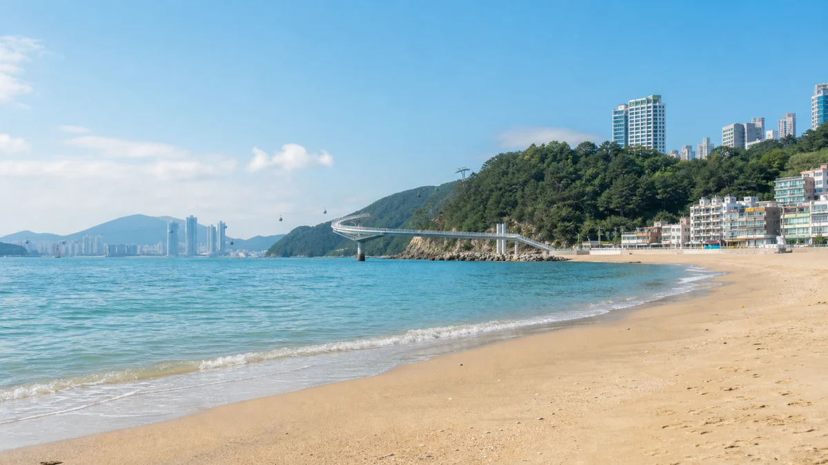 부산 송도해수욕장에 주황빛 저녁 햇살이 내려앉고 잔잔한 물결이 모래사장에 닿는 시간대 장면