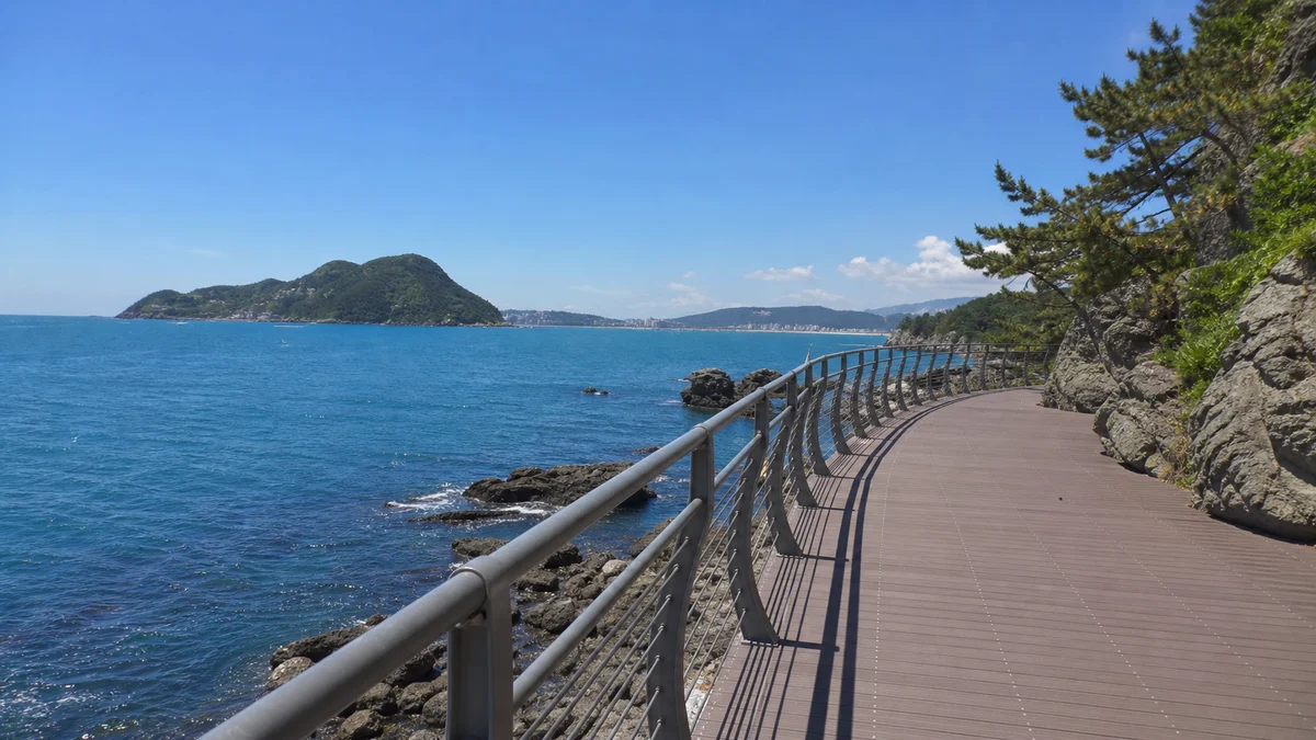 부산 송도구름산책로의 바다 위 데크와 난간, 해안 바위와 맞은편 섬이 보이는 산책 장면