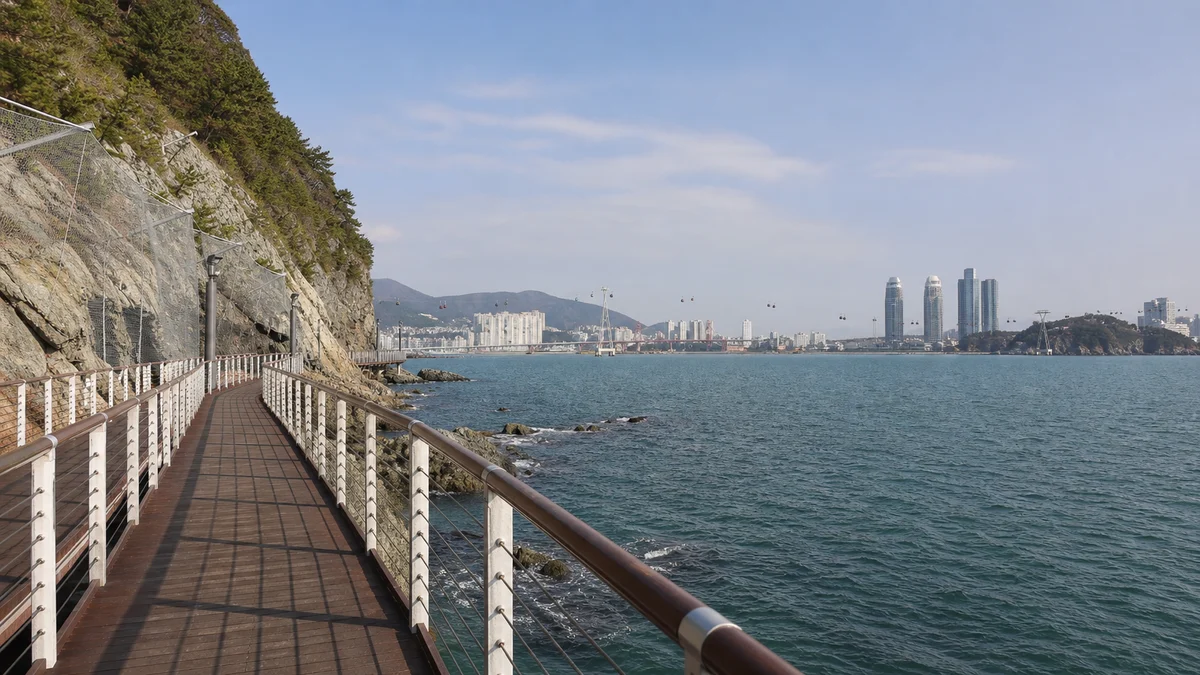 부산 송도구름산책로의 바다 위 데크와 난간, 해안 바위와 맞은편 섬이 보이는 산책 장면