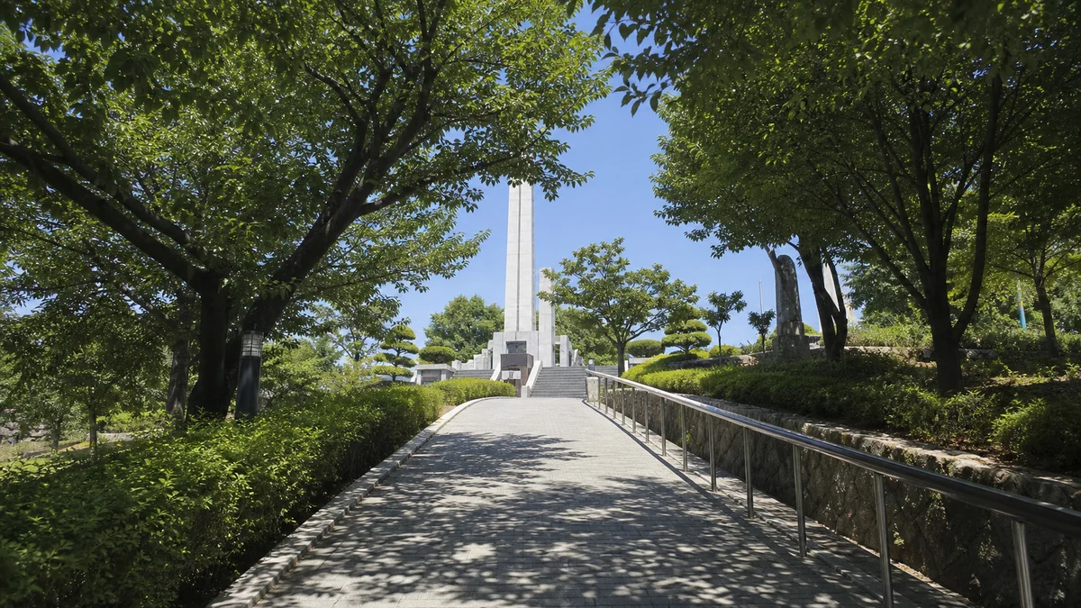 그늘진 포장 산책로와 난간을 따라 충혼탑으로 접근하는 동선, 여름 한낮