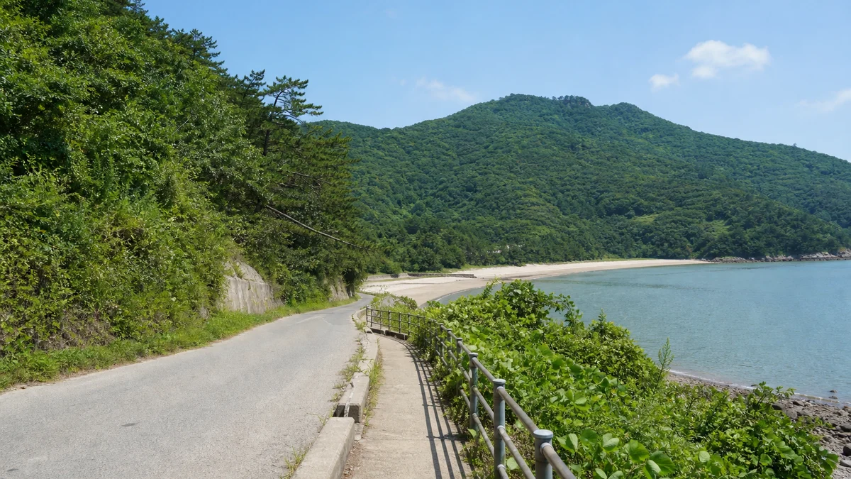사량대항해수욕장으로 이어지는 섬 해안도로와 난간 있는 보행 동선, 오른쪽으로 열린 바다