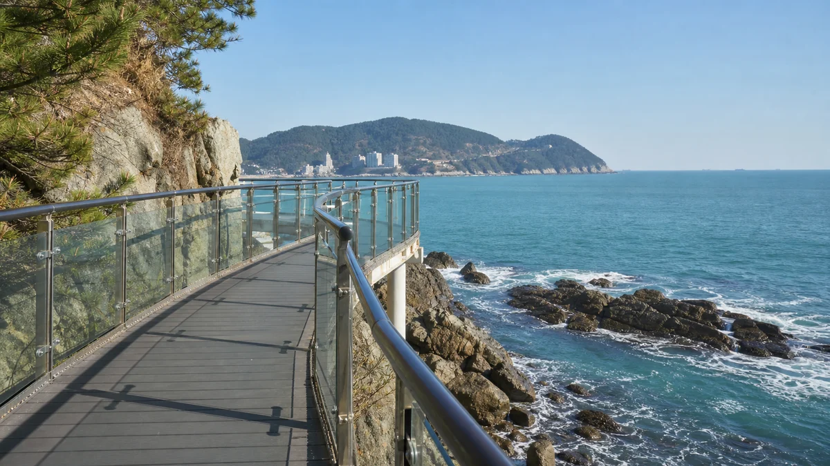 부산 송도구름산책로의 바다 위 보행 데크와 난간, 해안 바위와 맞은편 해안이 보이는 산책 장면