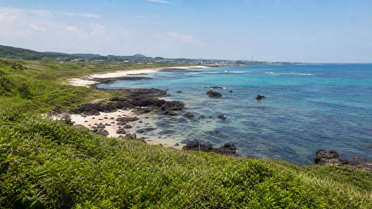제주 소금막해변 주변의 낮은 해안 식생과 열린 바닷가 공간, 멀리 보이는 소박한 마을 맥락